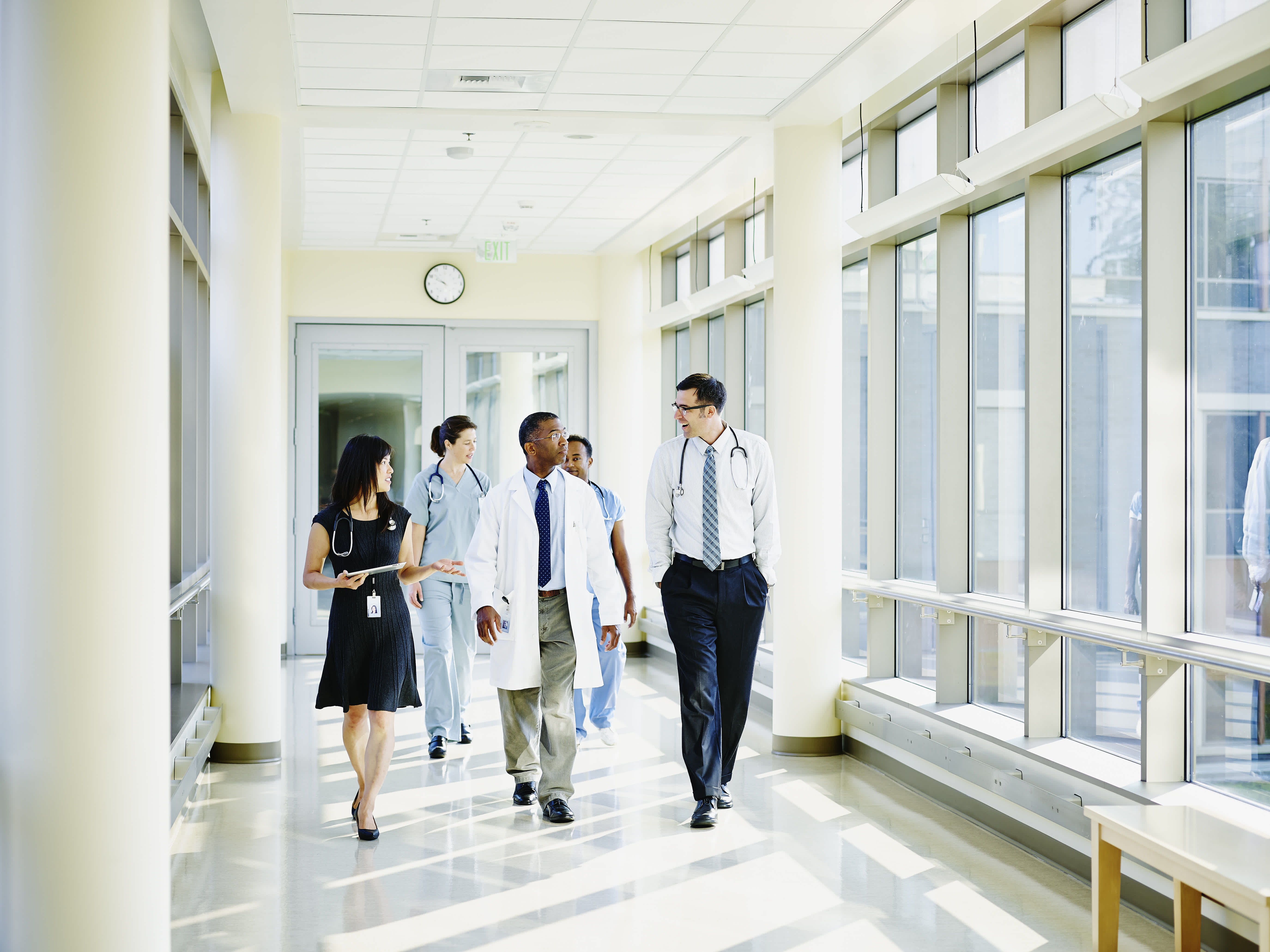 Five physicians walking along hospitals windows